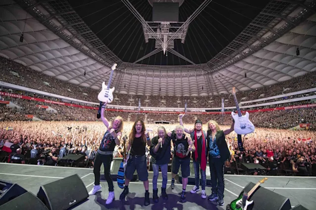 A smartphone showing verified concert ticket information inside a large empty stadium.
